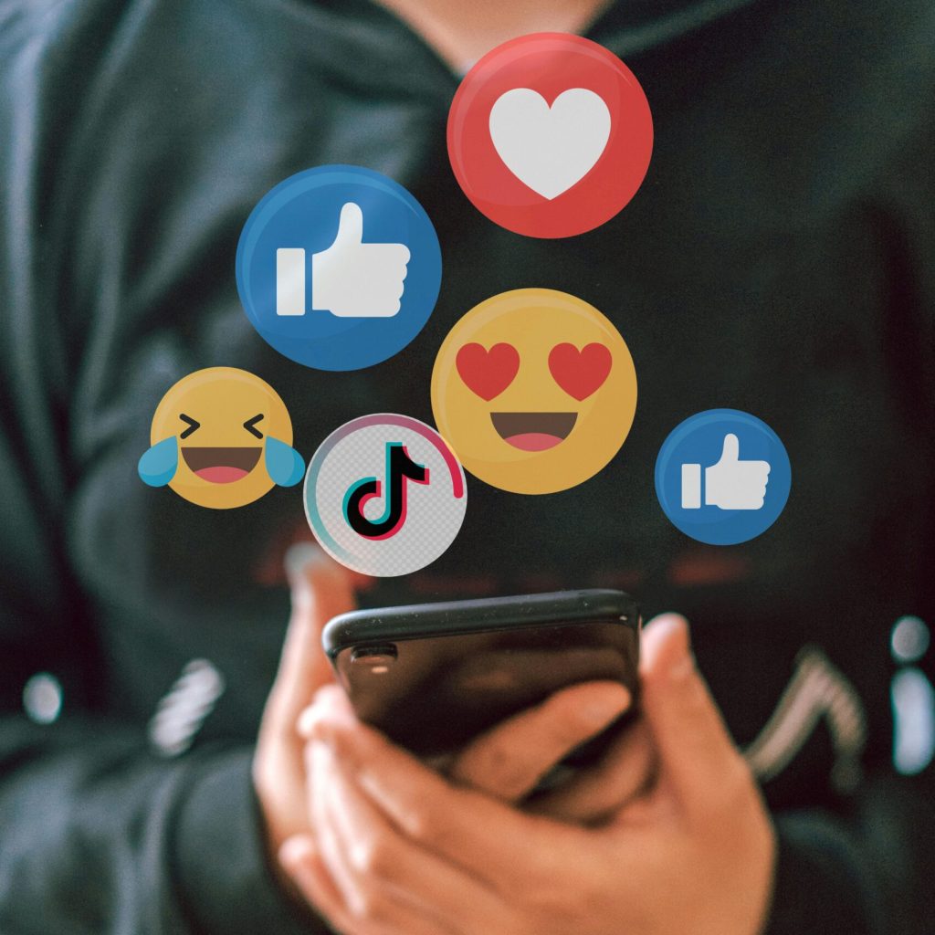 A teenager interacts with social media icons floating over a smartphone, illustrating digital connectivity and engagement.